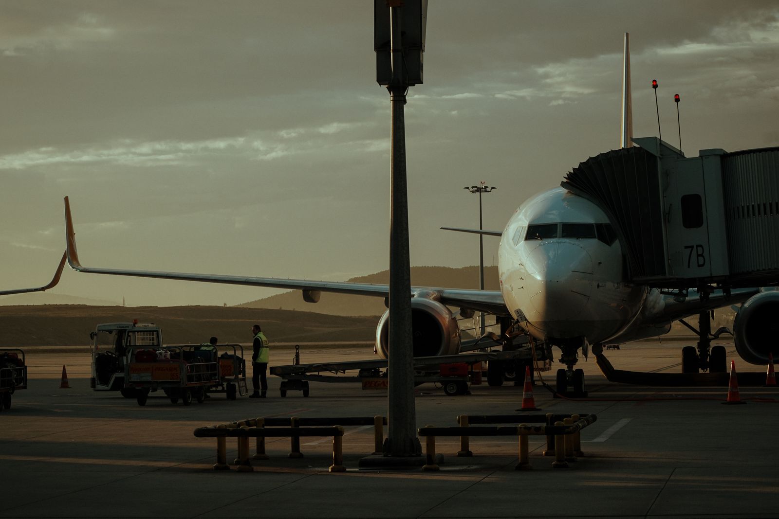 An aircraft on the apron at dusk with ground crew at work