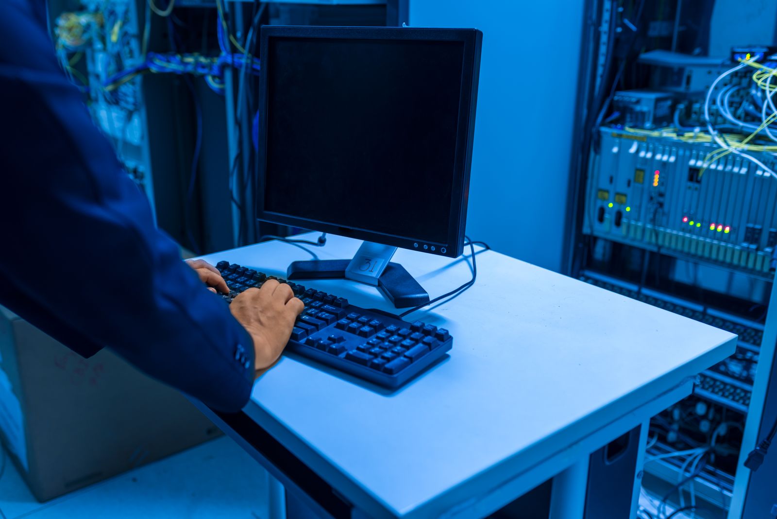 Someone working on a laptop in a dimly lit room