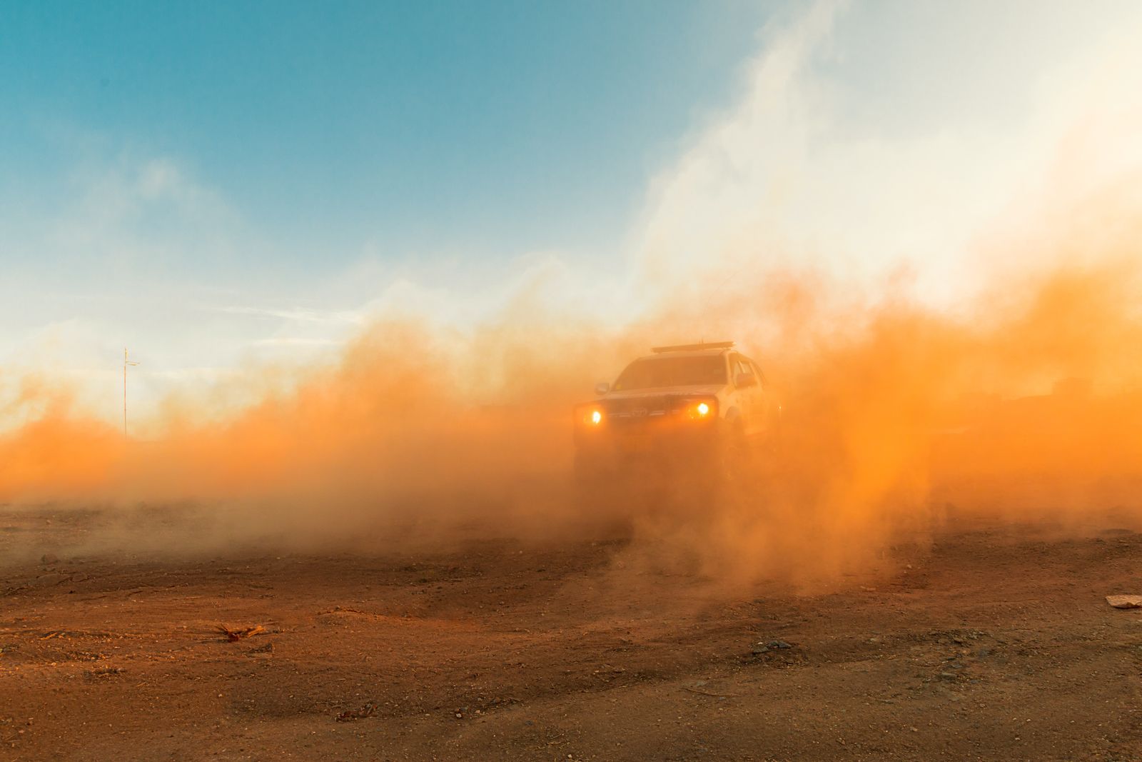 A four-wheel-drive vehicle kicking up dust on a gravel track