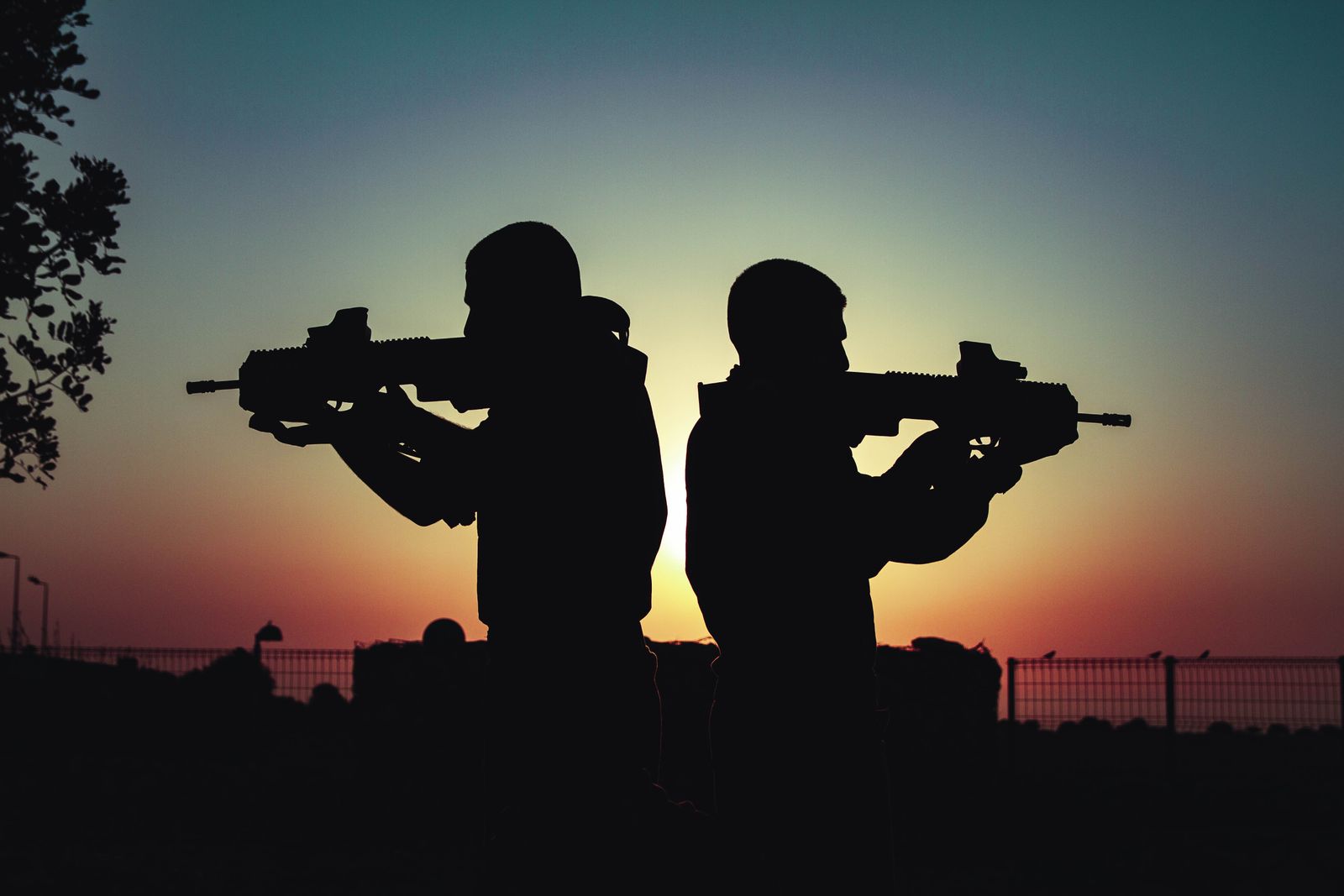 Two figures silhouetted against a vivid sunset sky