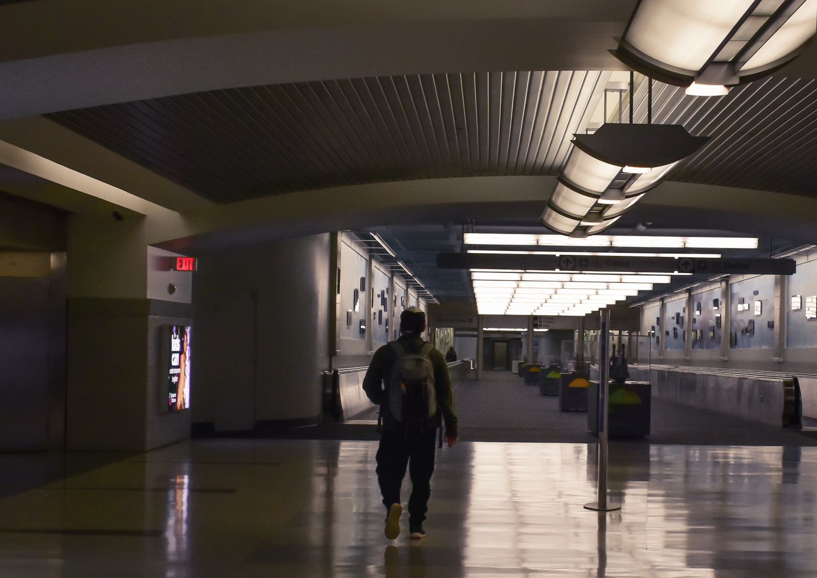 A traveller silhouetted in a dimly lit airport terminal at night