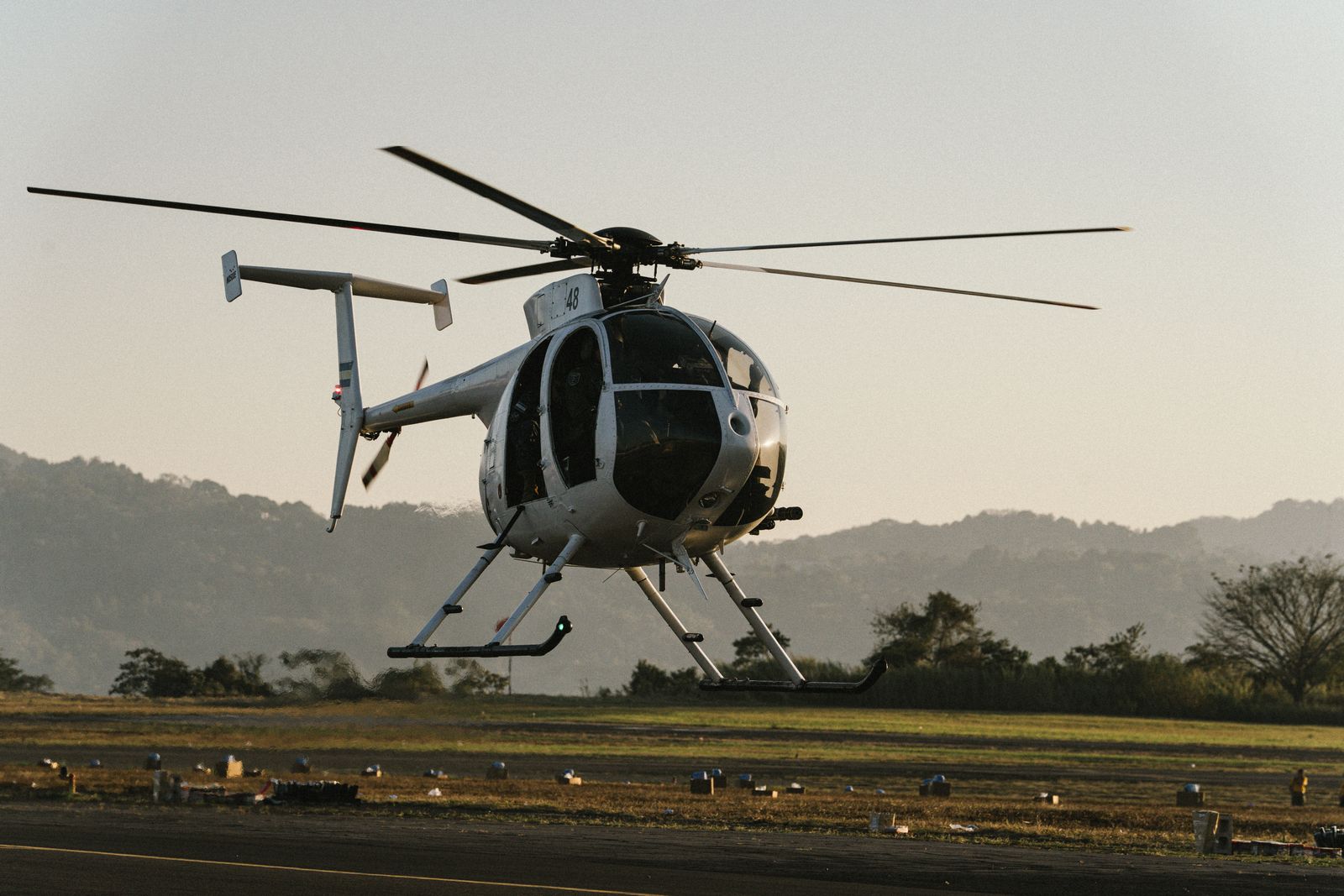 A helicopter on the ground at sunset, preparing to take off