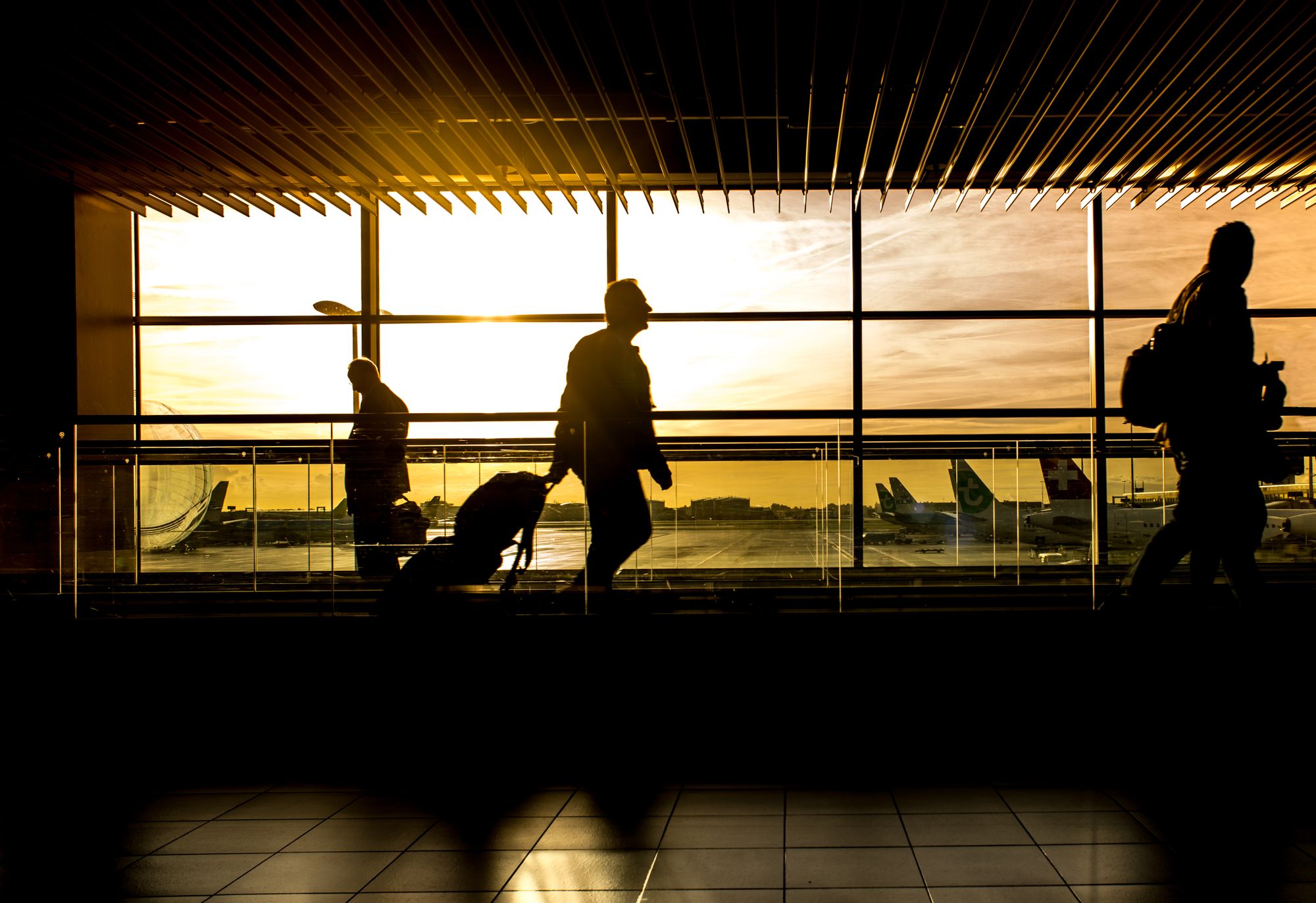 A traveller silhouetted against an airport terminal window at sunset