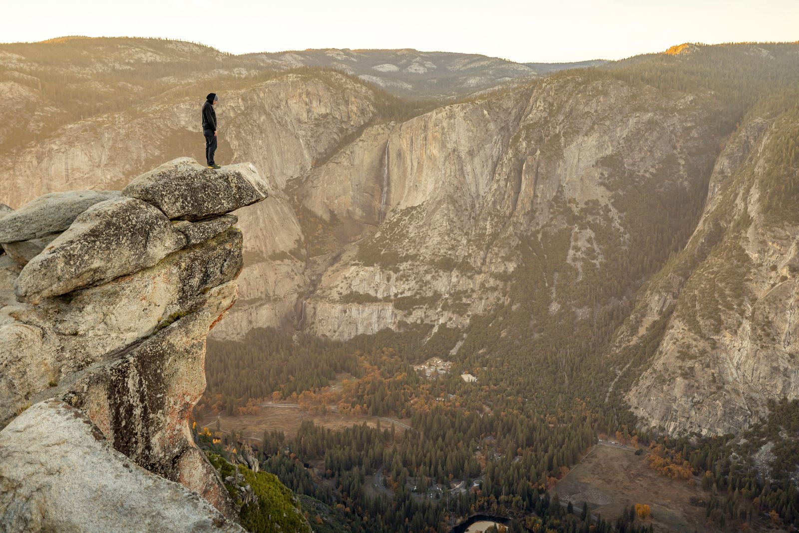 A lone figure looking out over a mountain valley at sunset