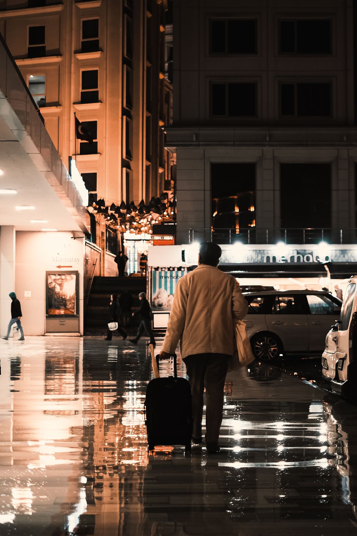 A traveller with luggage on a city street at night