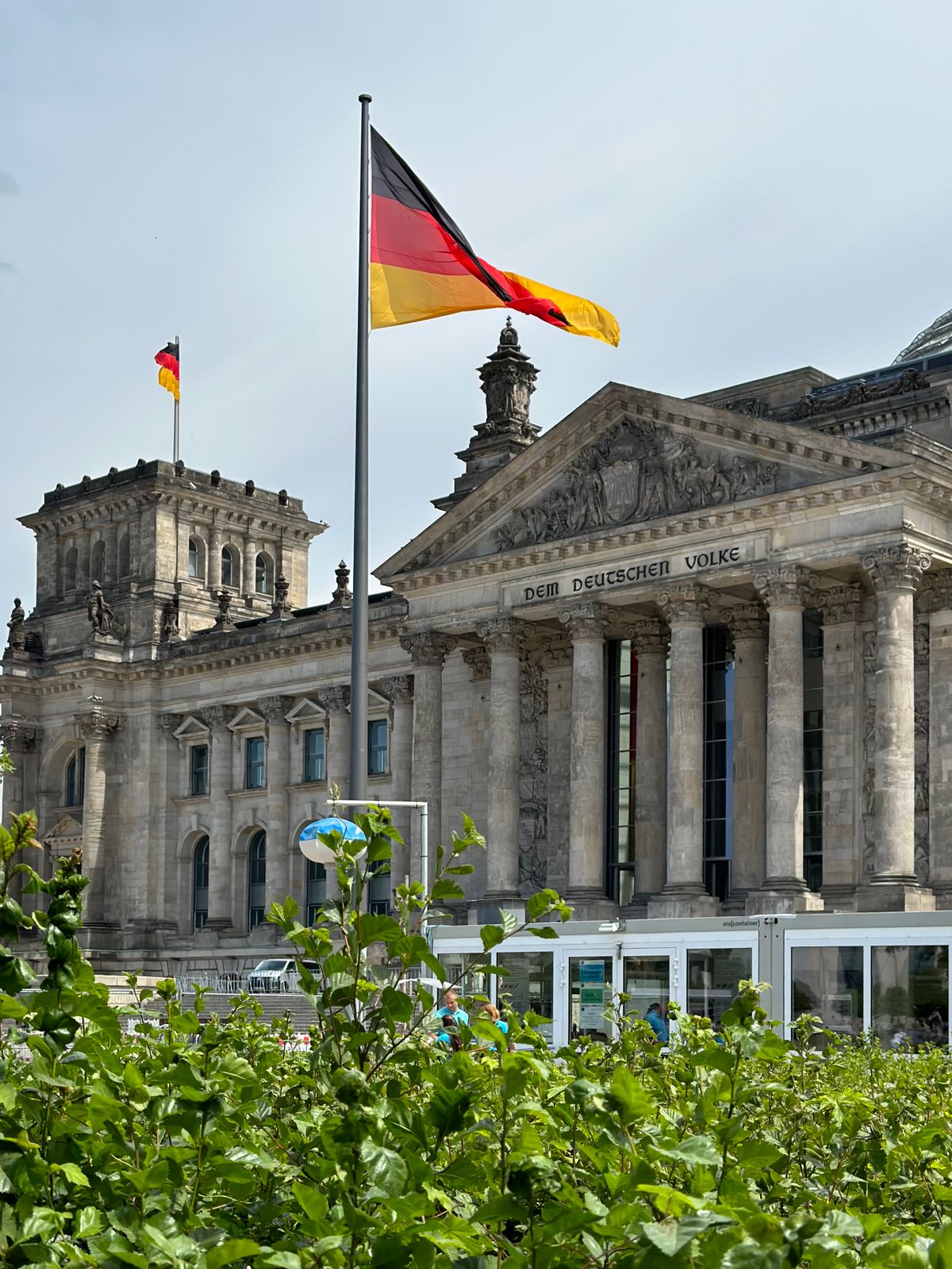 A historic parliament building flying national flags